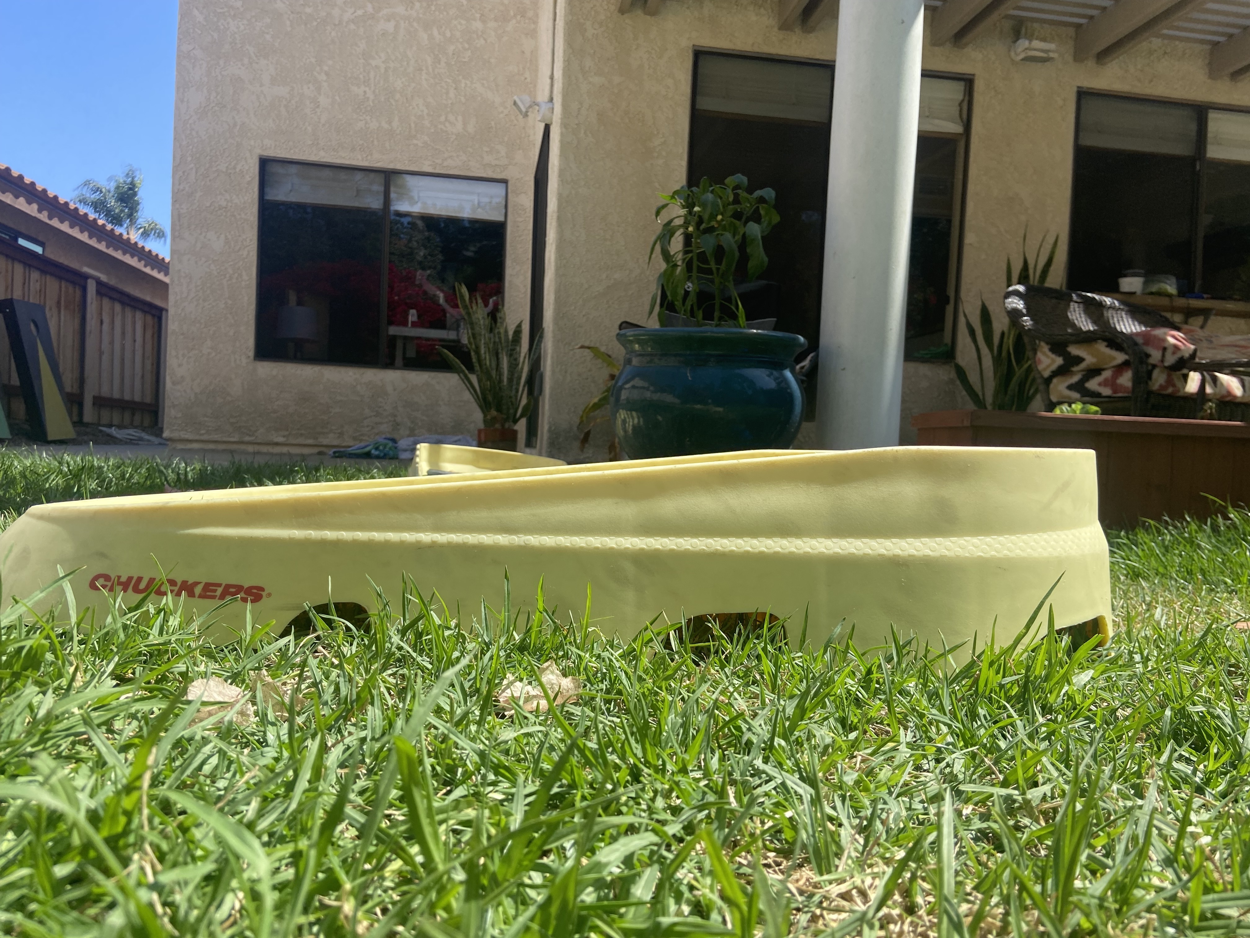 Side view of a Chuckers board in the grass on a sunny afternoon.